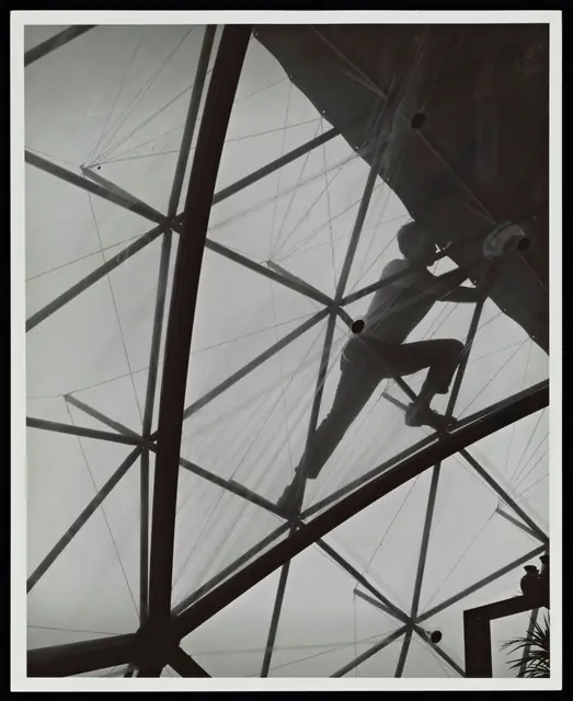 A man on the frame tensioning the skin, seen from below.