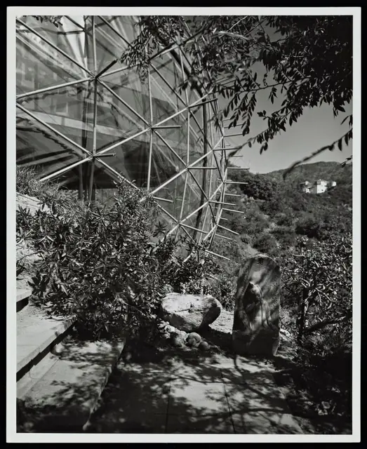 The dome seen through foliage and boulders on the hillside.